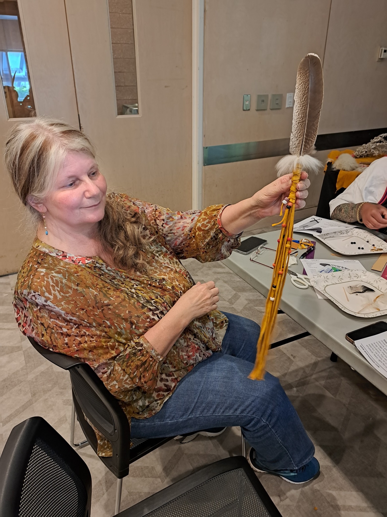 A woman holding her finished smudge feather at an Indigenous cultural workshop hosted by Miskwaadesi Studio in Richmond Hill, Ontario