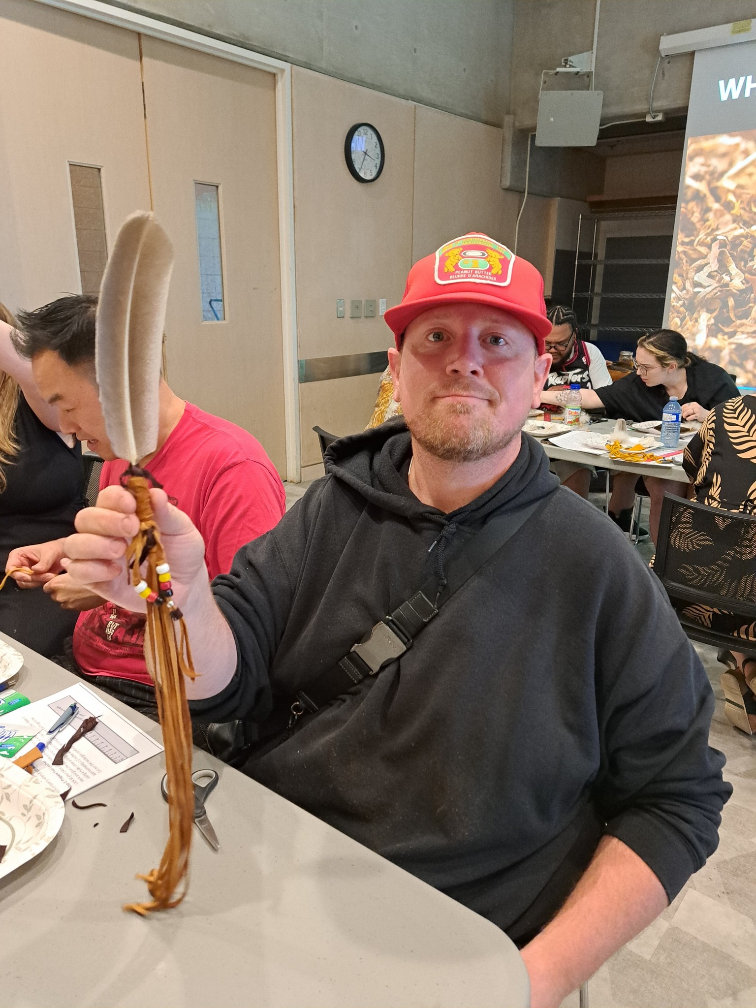 A man holding a finished smudge feather during an Indigenous cultural workshop by Miskwaadesi Studio in Richmond Hill, Ontario