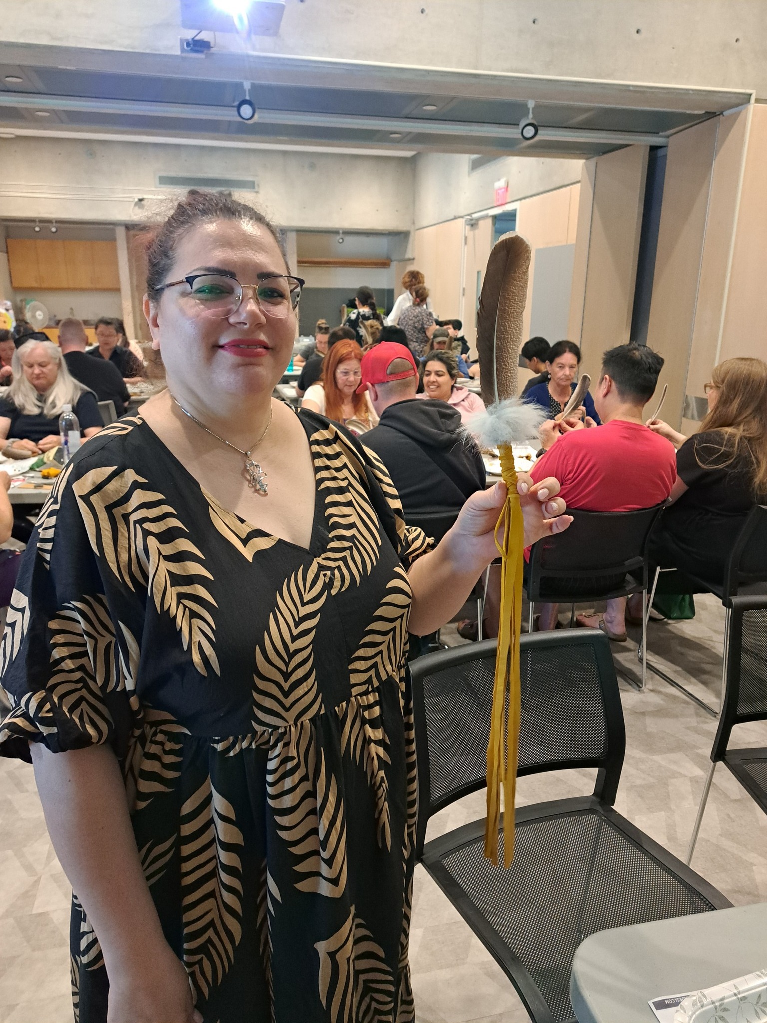 A woman holding up a handmade smudge feather during a Miskwaadesi Studio workshop at Central Library in Richmond Hill, Ontario.