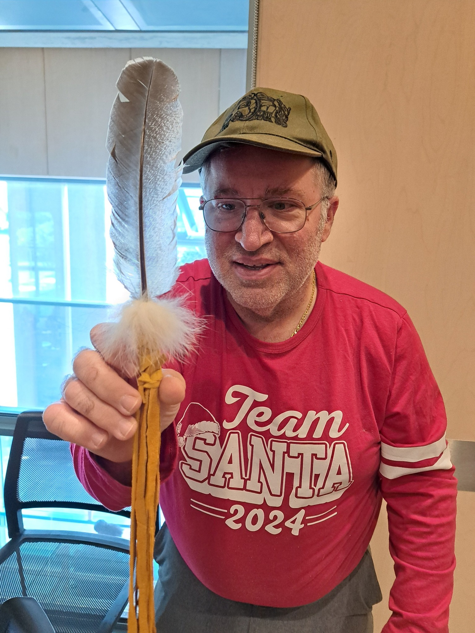A man holding his finished smudge feather at an Indigenous workshop hosted by Miskwaadesi Studio in Richmond Hill, Ontario